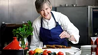 Chef sprinkling herbs on dish
