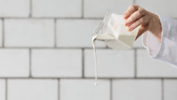 person pouring milk from glass container