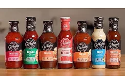 Assortment of zero-sugar condiments and sauces, including sweet chili sauce, barbecue sauce, ketchup, ranch dressing, and teriyaki marinade, displayed on a countertop.