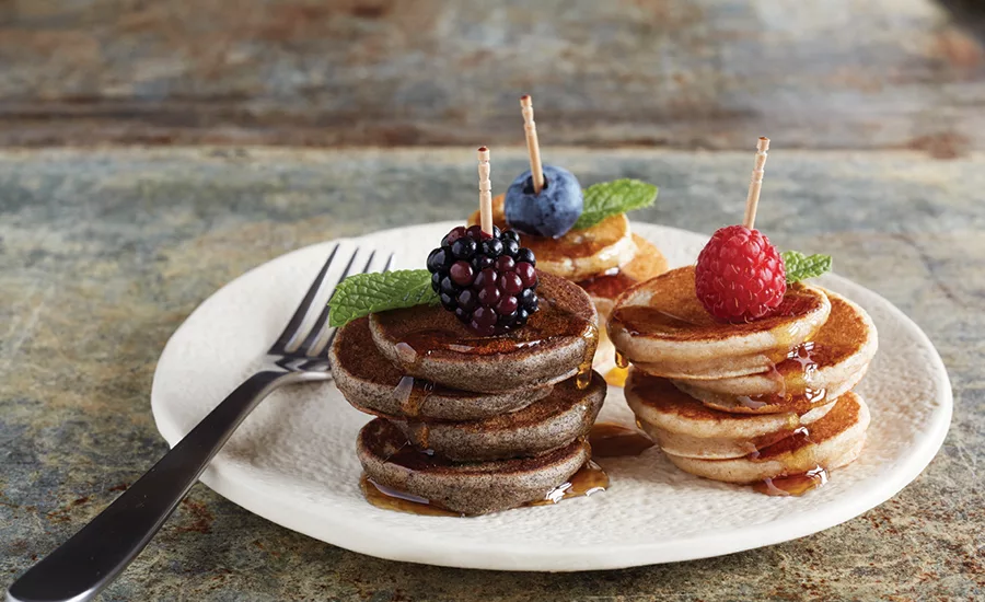 Three Stacks of Mini Pancakes Each Topped with a Berry