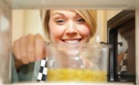 Woman Looking at Pouch in Microwave