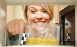 Woman Looking at Pouch in Microwave