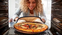 Woman taking pizza out of oven