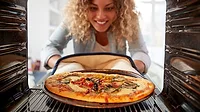 Woman taking pizza out of oven