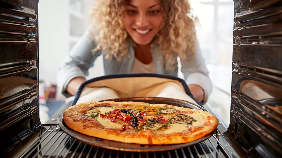 Woman taking pizza out of oven
