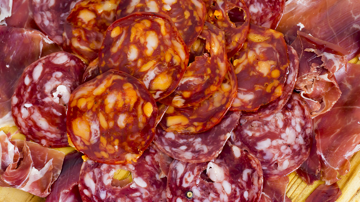 A close-up of a vibrant platter showcasing a variety of sliced cured meats like chorizo, salami, and prosciutto.