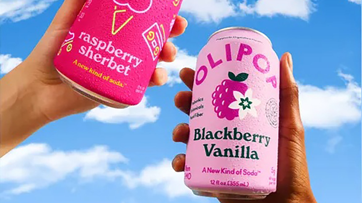Two hands hold Olipop Raspberry Sherbet and Blackberry Vanilla cans against a blue sky with cloud lettering.