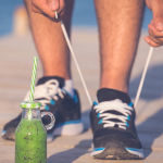 Person Tying Shoes Next to Green Health Drink