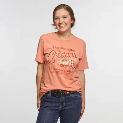 A woman is wearing a 'Bringing Home the Cheddar' Cabot t-shirt.