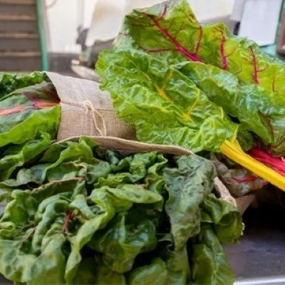 Bunches of kale wrapped in bags with loose leaves on top of them.